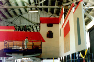 Eleanor Holmes on scissor lift painting the mercado set